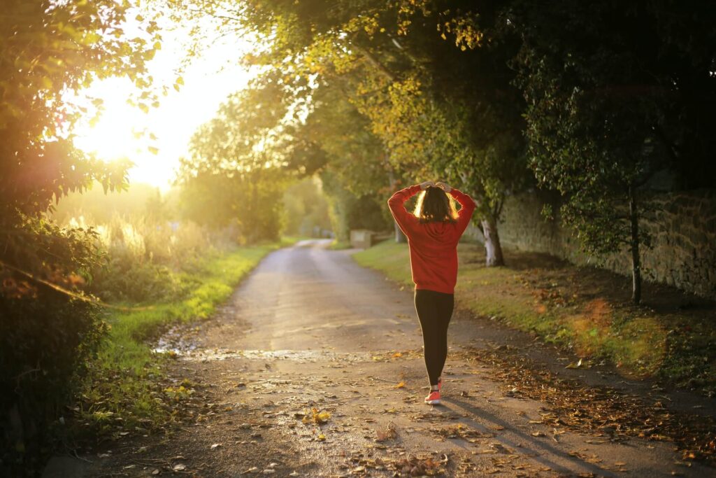 woman running into the sun on dirt trail